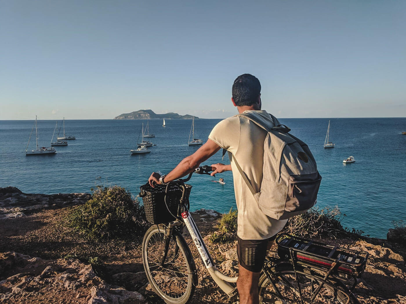 guy on a bicycle on a  cliff looking over the ocean in favignana island sicily